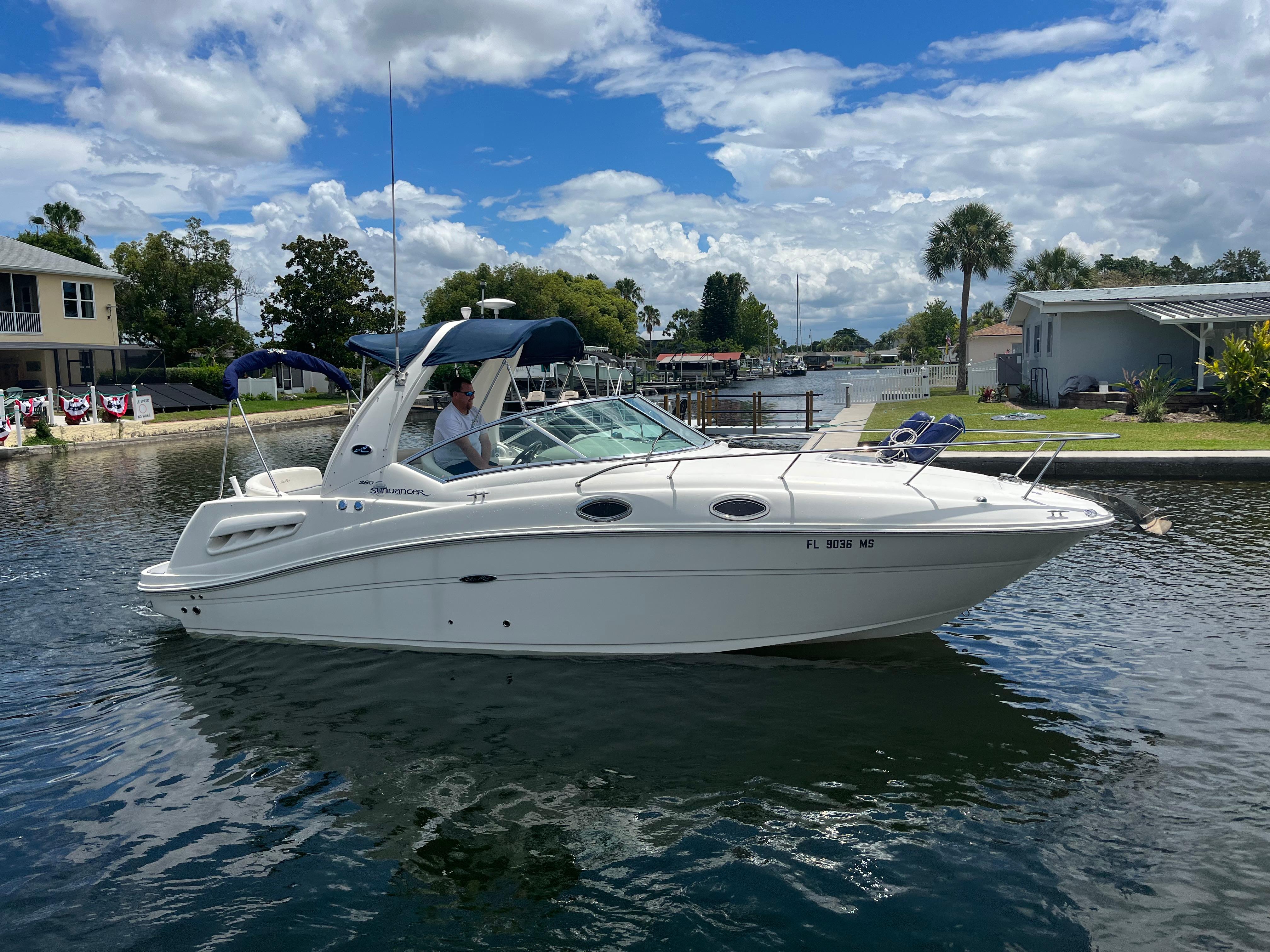 Sea Ray 260 Sundancer 2005 Sea Ray 260 Sundancer boat cruising on a sunny day in a residential canal.