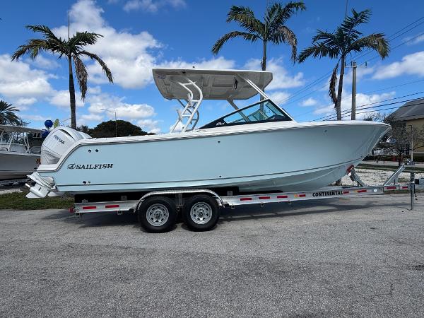 Sailfish 276 DC 2025 Sailfish 276 DC boat on trailer, parked with palm trees in background.