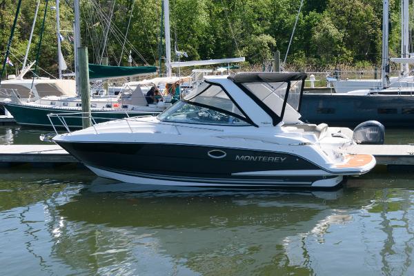 Monterey 295 Sport Yacht 2019 Monterey 295 Sport Yacht docked at marina, surrounded by sailboats and lush greenery.