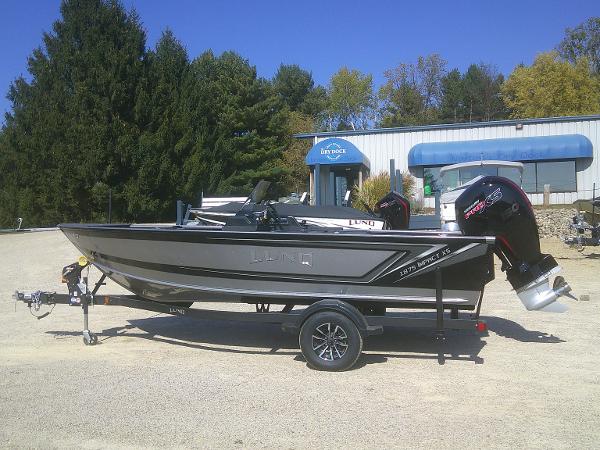 Lund 1875 Impact XS SS 2025 Lund 1875 Impact XS SS boat on trailer, parked outdoors near a building.