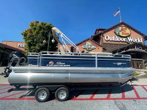Sun Tracker Fishin' Barge 20 DLX 2025 Sun Tracker Fishin' Barge 20 DLX pontoon boat outside Bass Pro Shops.