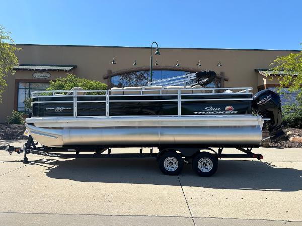 Sun Tracker SportFish 20 DLX 2025 Sun Tracker SportFish 20 DLX pontoon boat on trailer, parked outdoors.