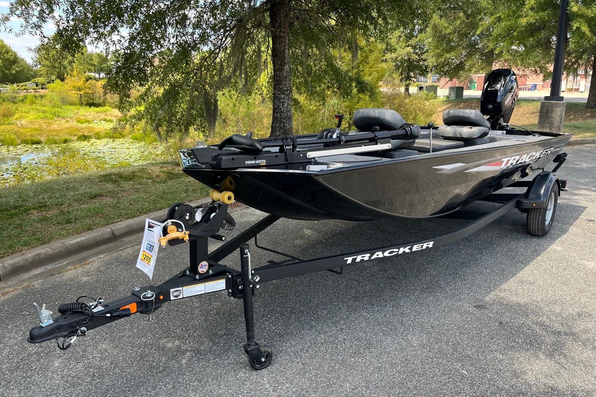 Tracker Panfish 17 2025 Tracker Panfish 17 boat on trailer, parked outdoors near a pond.