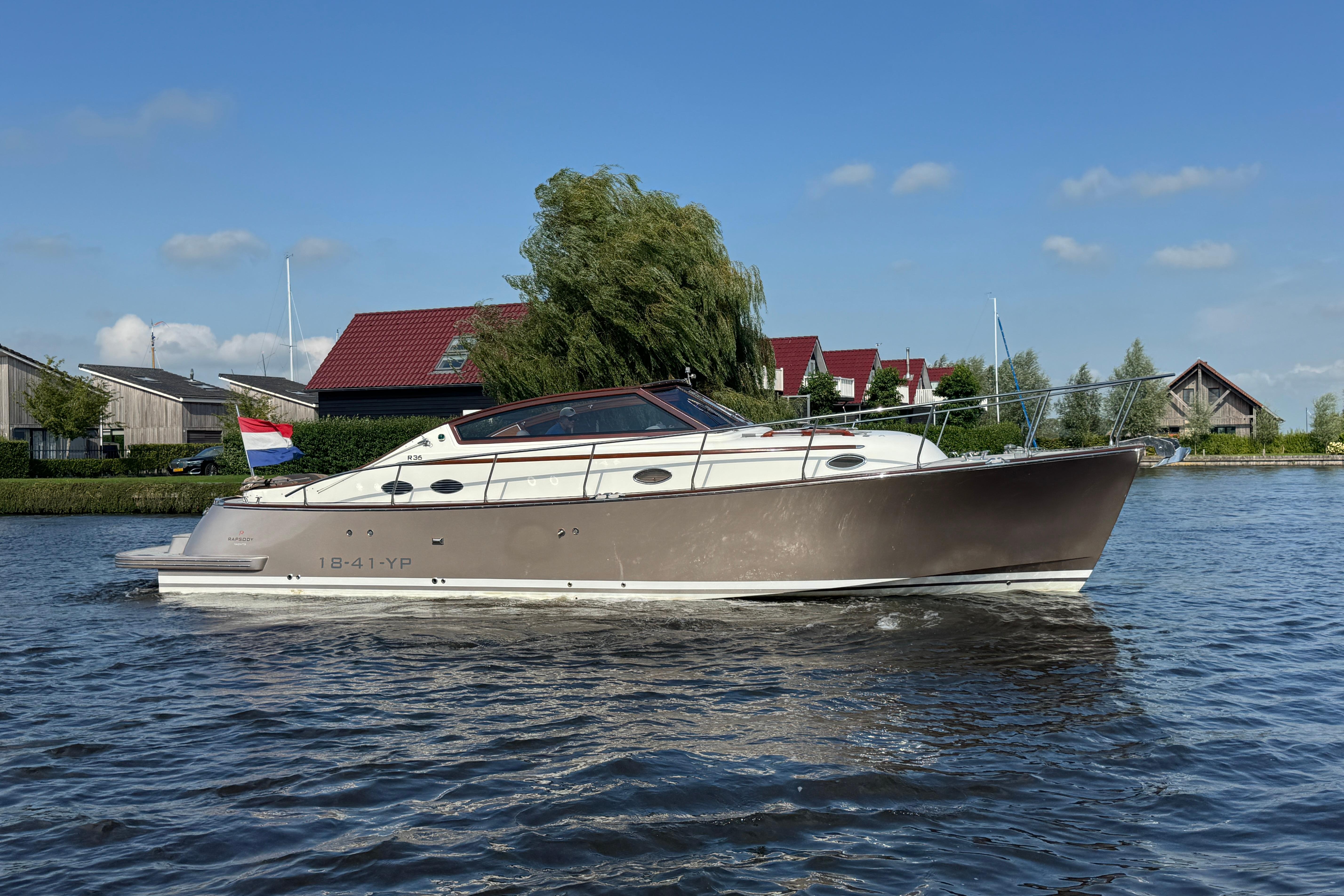Rapsody R36 SE 2009 Rapsody R36 boat cruising on a calm river with houses in the background.