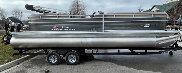 Sun Tracker Party Barge 24 DLX 2025 Sun Tracker Party Barge 24 DLX pontoon boat on trailer, parked outdoors.
