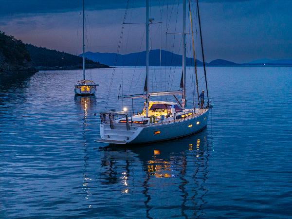 Amel 55 Sailboats anchored at dusk on calm water, featuring a 2018 Amel 55 model.