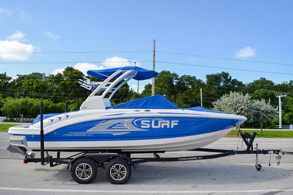 Chaparral 23 Surf 2021 Chaparral 23 Surf boat on trailer, blue and white design, parked on road.