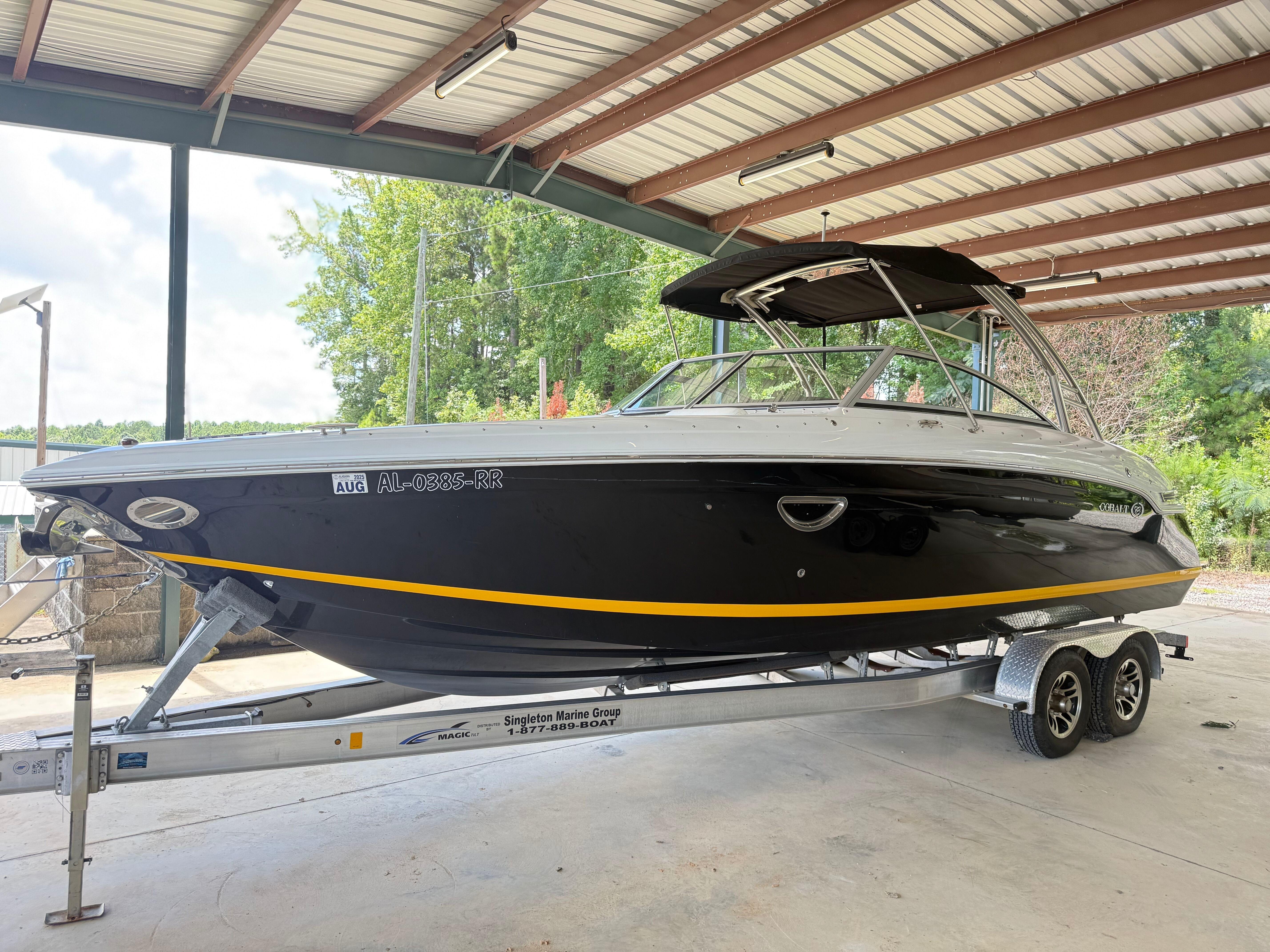 Cobalt 276 2012 Cobalt 276 boat on trailer under a metal roof, side view.