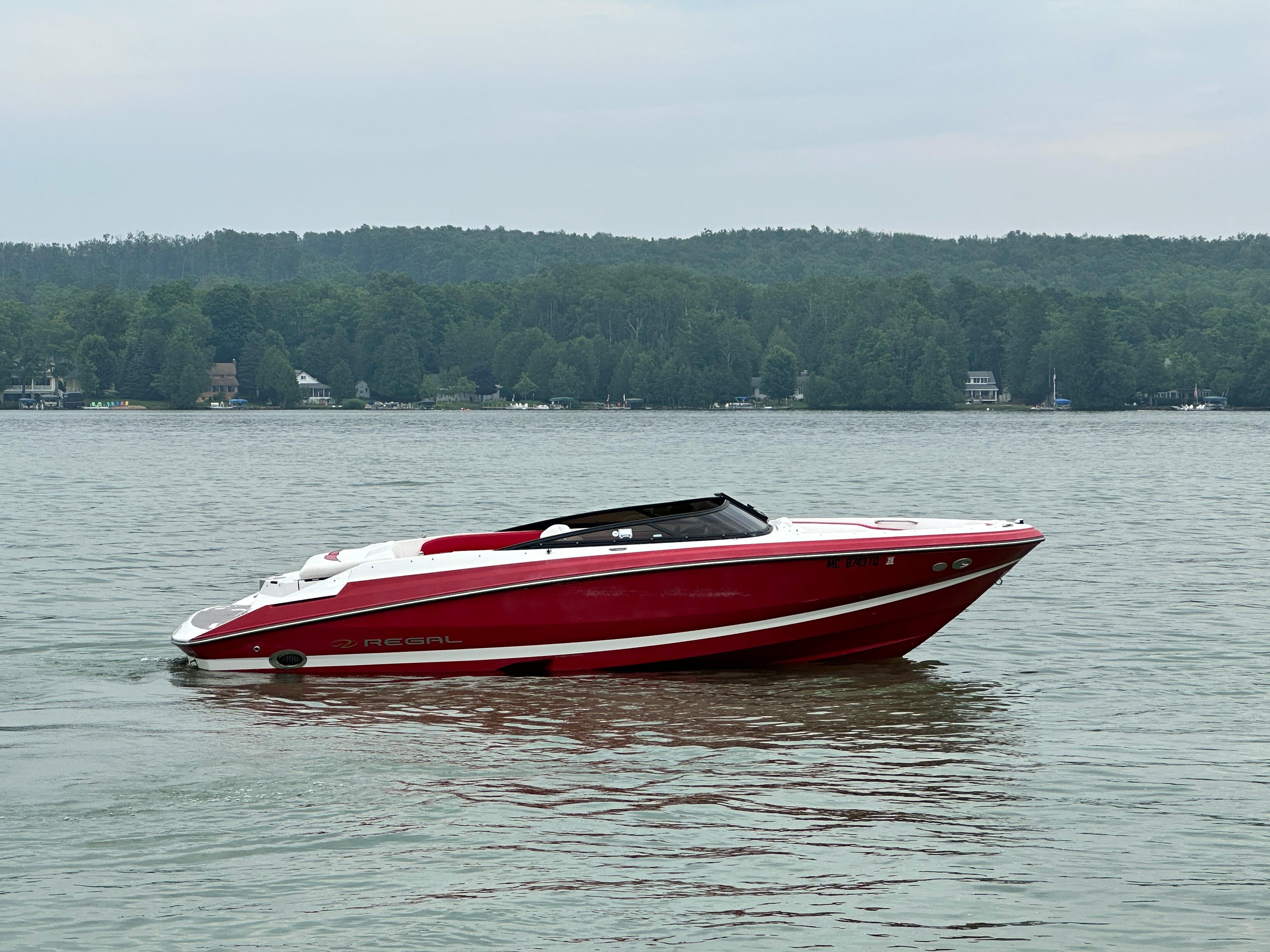 Regal 2200 RS 2008 Regal 2200 RS boat on a calm lake with forested shoreline.