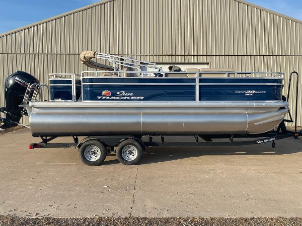 Sun Tracker Fishin' Barge 20 DLX 2025 Sun Tracker Fishin' Barge 20 DLX pontoon boat on trailer, parked outdoors.