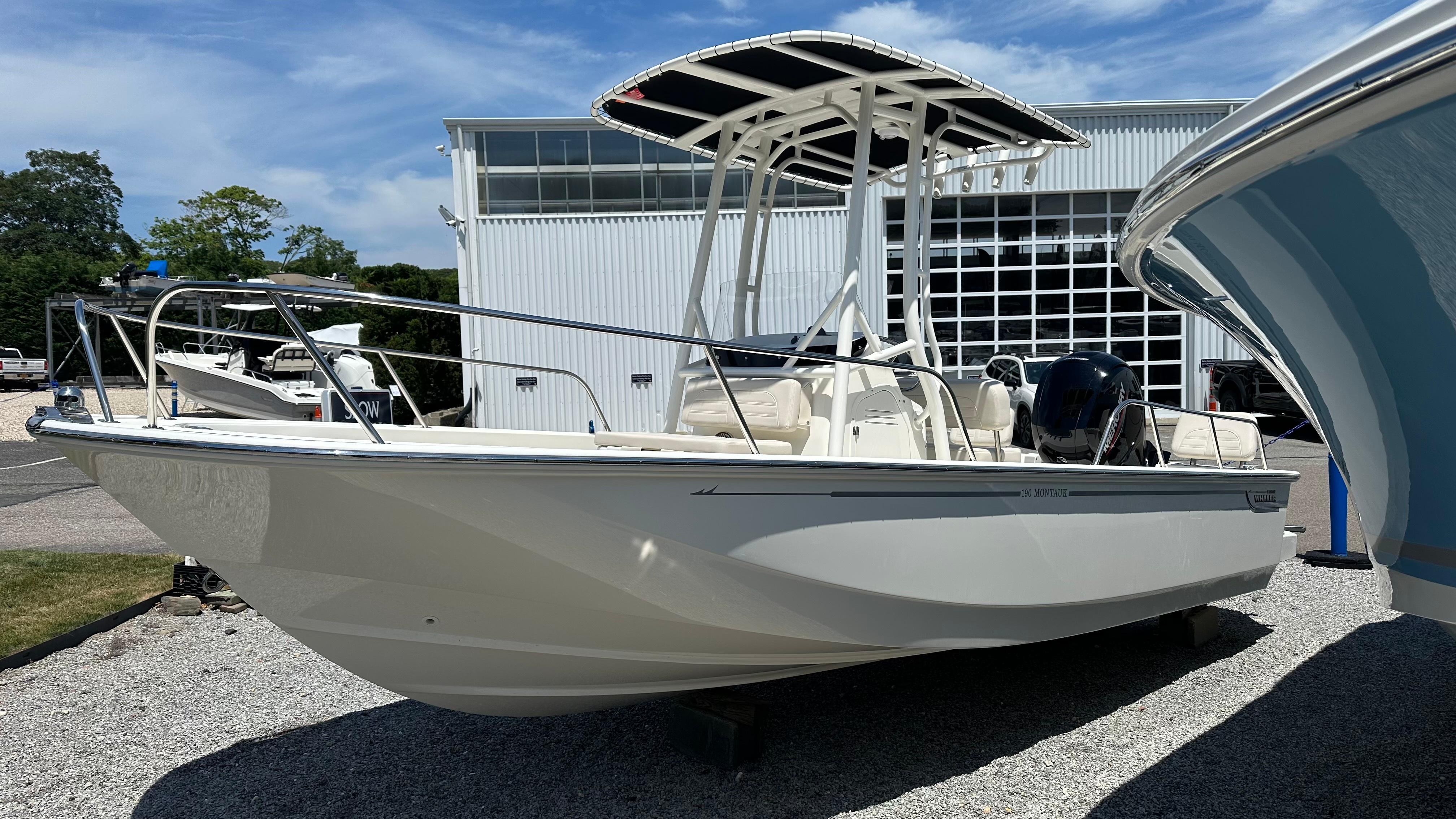 Boston Whaler 190 Montauk 2025 Boston Whaler 190 Montauk boat displayed outdoors near a modern building.