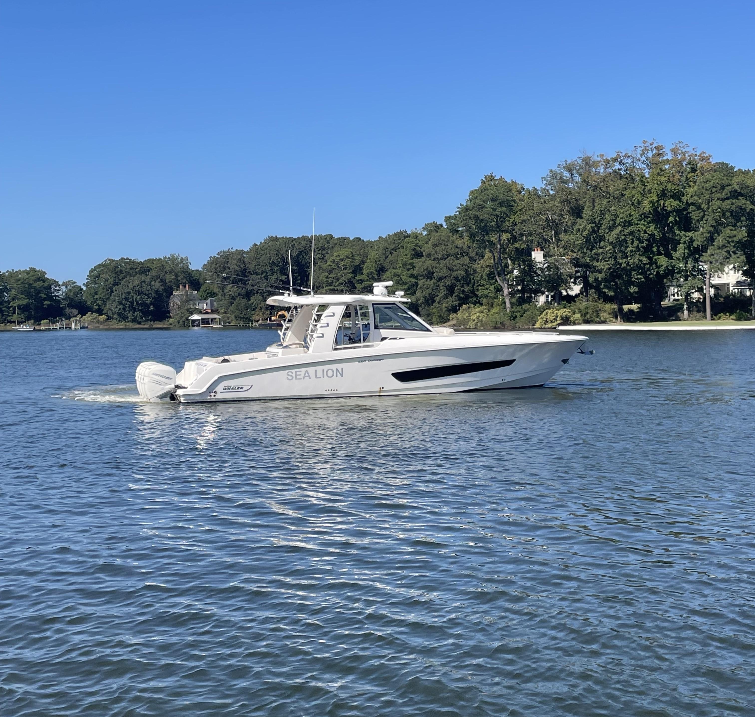 Boston Whaler 420 Outrage 2019 Boston Whaler 420 Outrage boat on calm water, surrounded by trees.