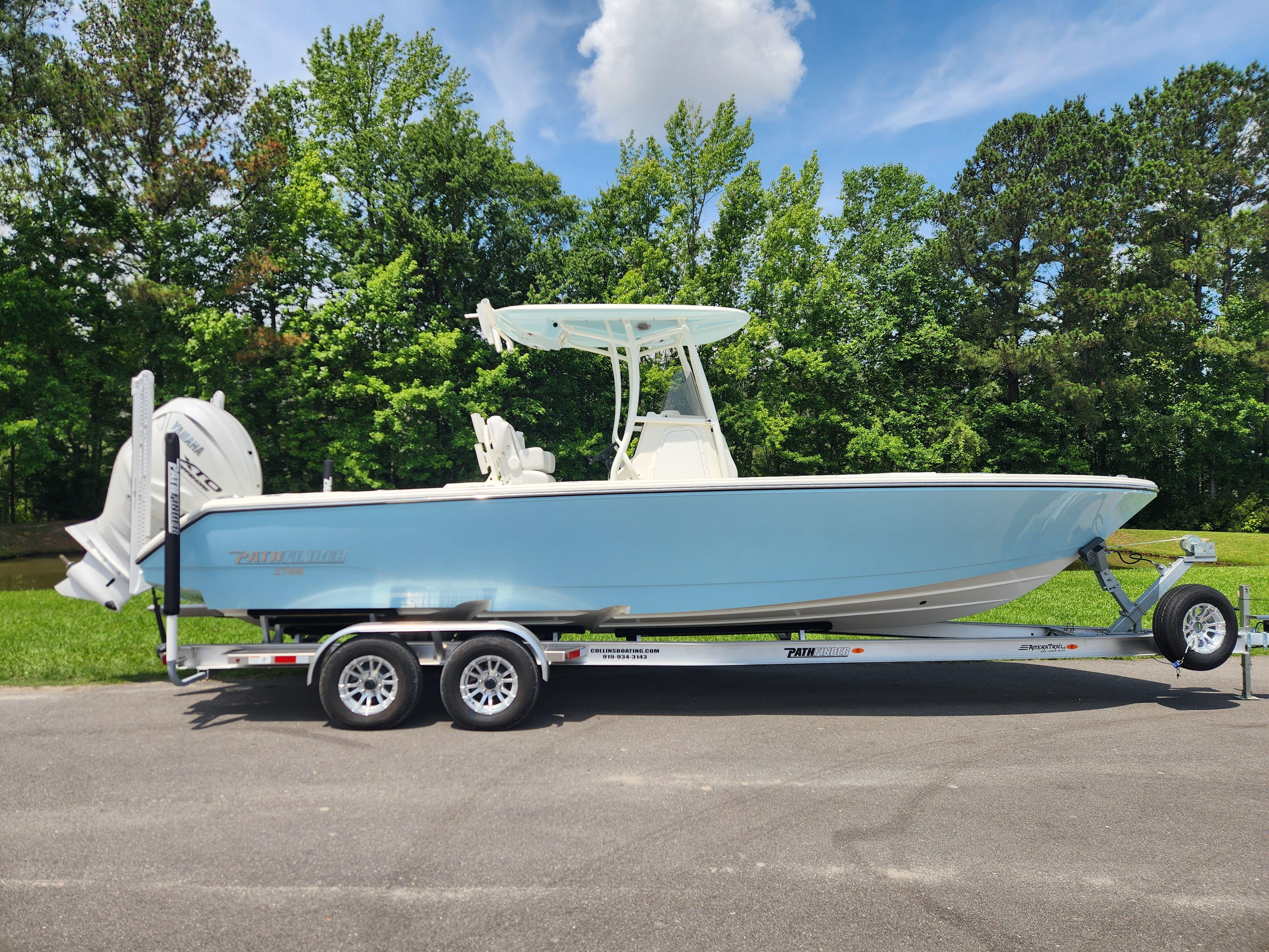 Pathfinder 2700 Open 2024 Pathfinder 2700 Open boat on trailer, parked outdoors with lush green trees.