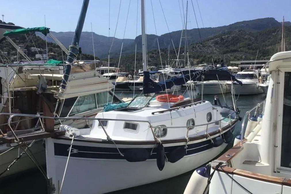 Myabca 26 1985 Myabca 26 sailboat docked in a marina, surrounded by other boats and scenic mountains.