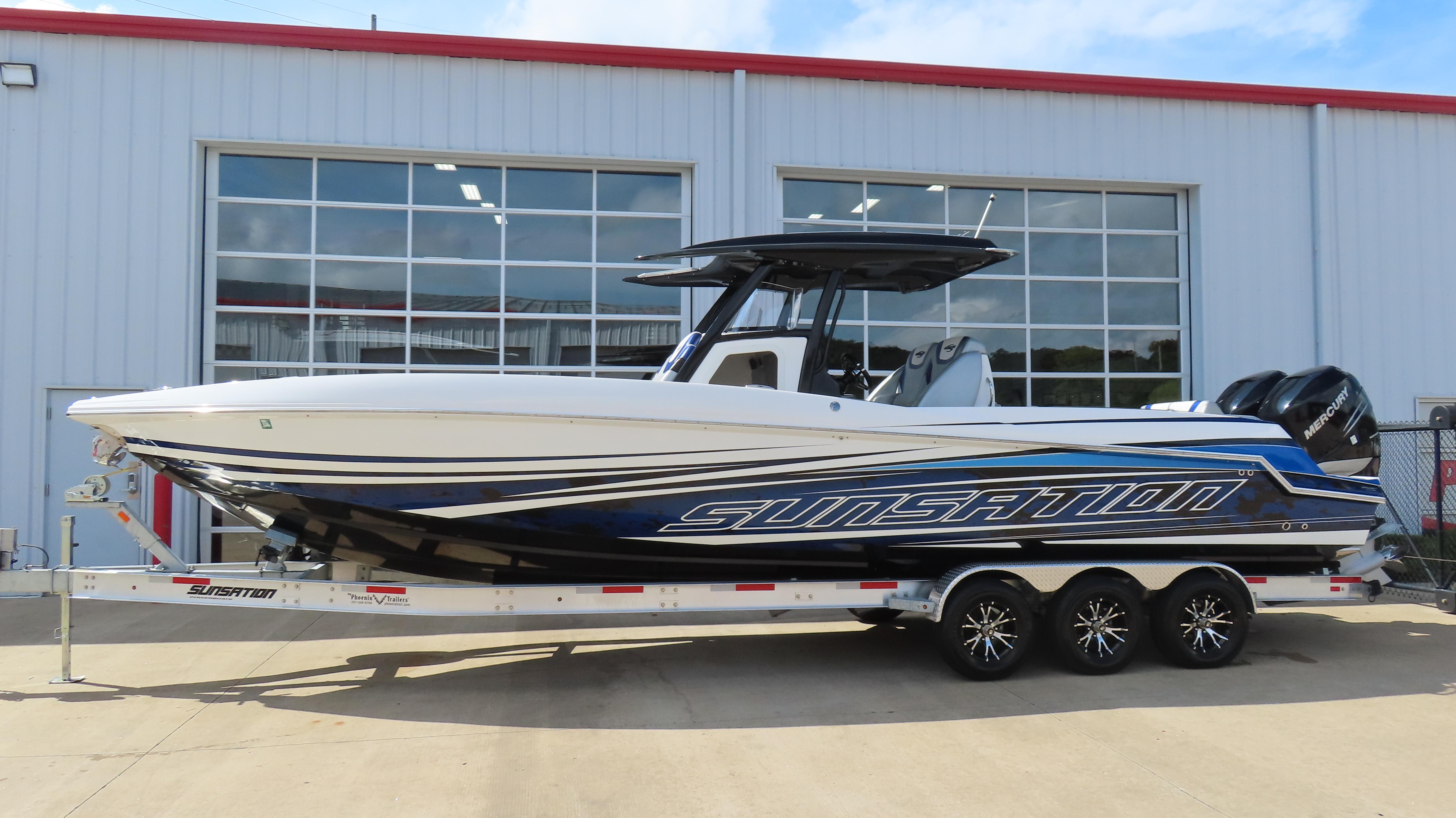 Sunsation 32 CCX 2017 Sunsation 32 CCX boat on trailer, parked outside a building.