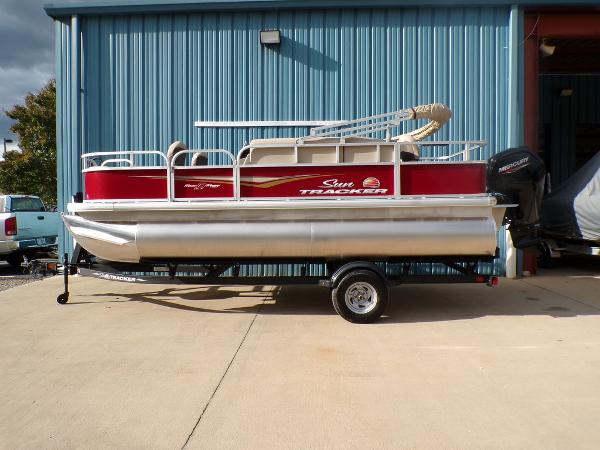 Sun Tracker Bass Buggy 18 DLX 2025 Sun Tracker BASS BUGGY® 18 DLX pontoon boat parked outside a blue building.