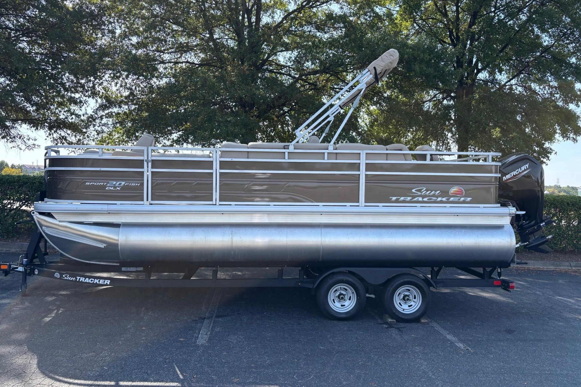 Sun Tracker SportFish 20 DLX 2025 Sun Tracker SportFish 20 DLX pontoon boat on trailer, parked outdoors.