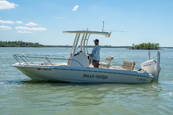 Boston Whaler 210 Dauntless 2020 Boston Whaler 210 Dauntless boat on water, man steering, clear sky.