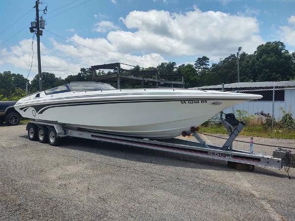 Fountain 32 Fever 1996 Fountain 32 Fever speedboat on trailer, parked outdoors under a partly cloudy sky.