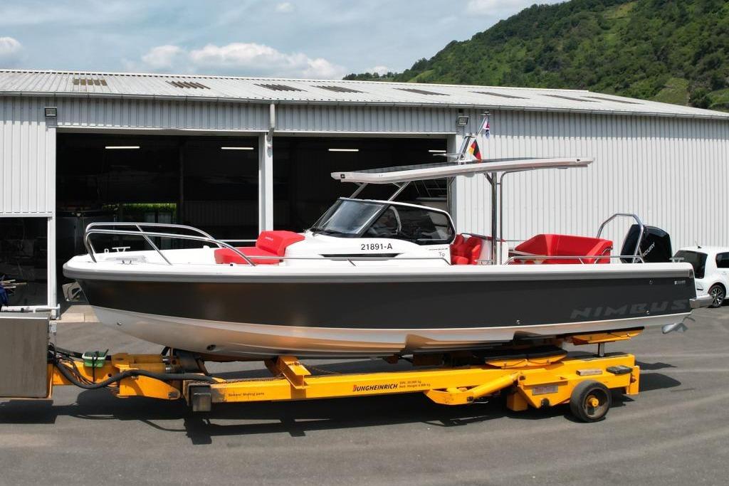 Nimbus T9 2022 Nimbus T9 boat on trailer outside a warehouse, featuring sleek design and red seating.