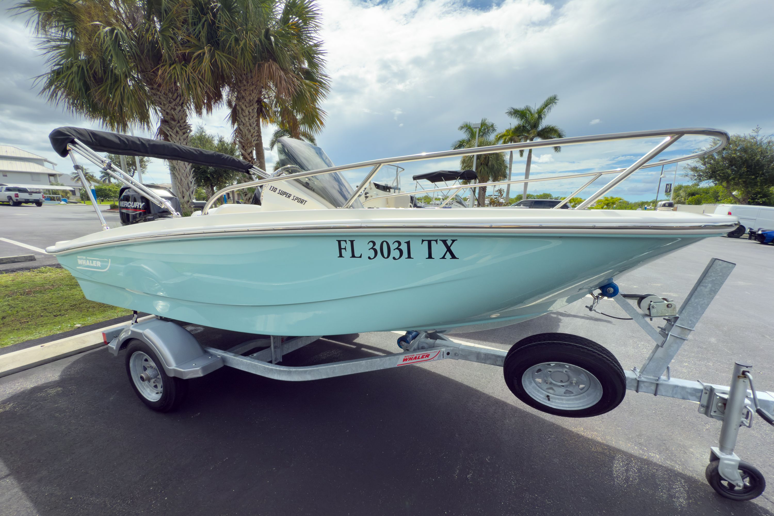 Boston Whaler 130 Super Sport 2025 Boston Whaler 130 Super Sport boat on trailer, parked near palm trees.