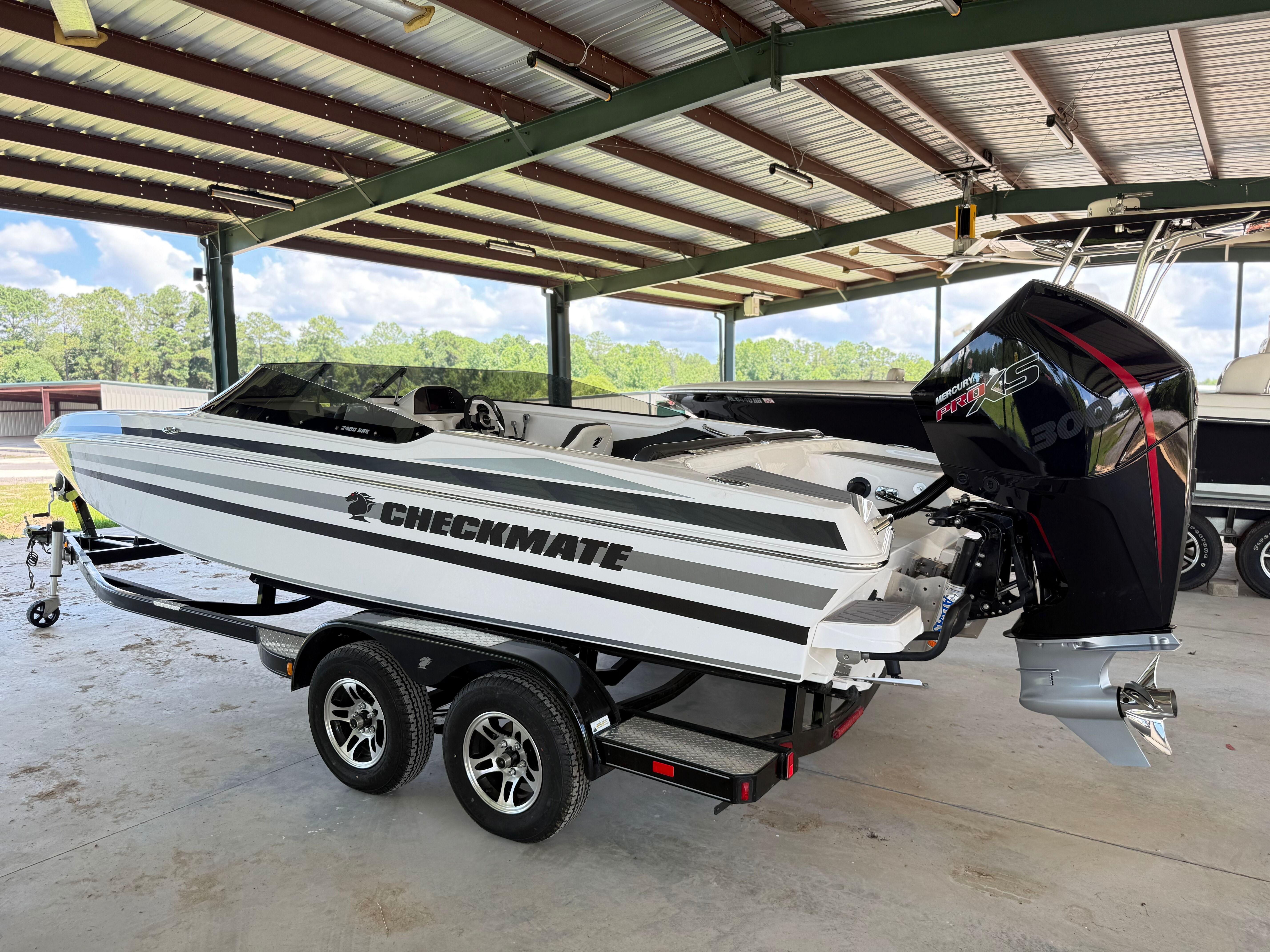 Checkmate Pulsare 2400 BRX 2024 Checkmate Pulsare 2400 BRX boat on trailer under shelter.