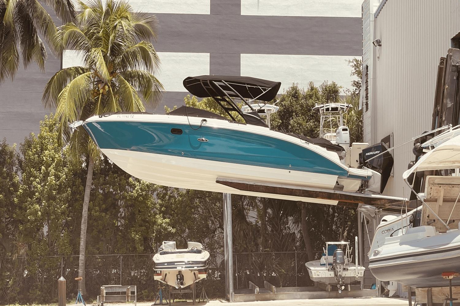 Sea Ray SDX 290 Outboard 2022 Sea Ray 290 SDX-OB boat in storage, surrounded by palm trees and other boats.
