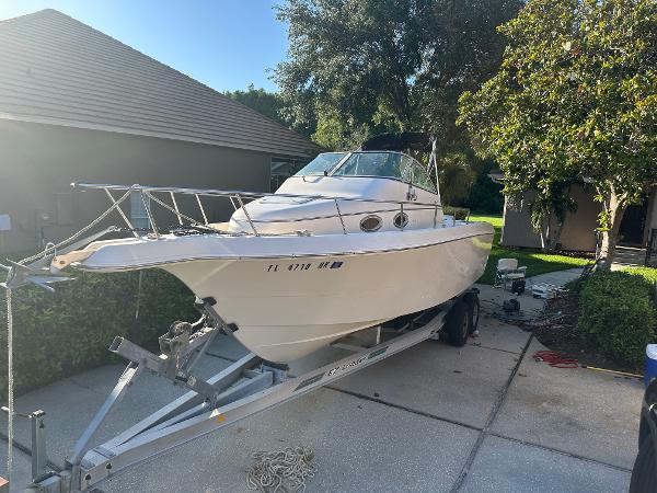 Pro-Line 251WA 1997 Pro-Line 251WA boat on trailer in driveway, surrounded by trees and houses.