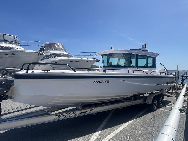Axopar 28 CABIN 2022 Axopar 28 CABIN boat on trailer, docked with other boats in background.