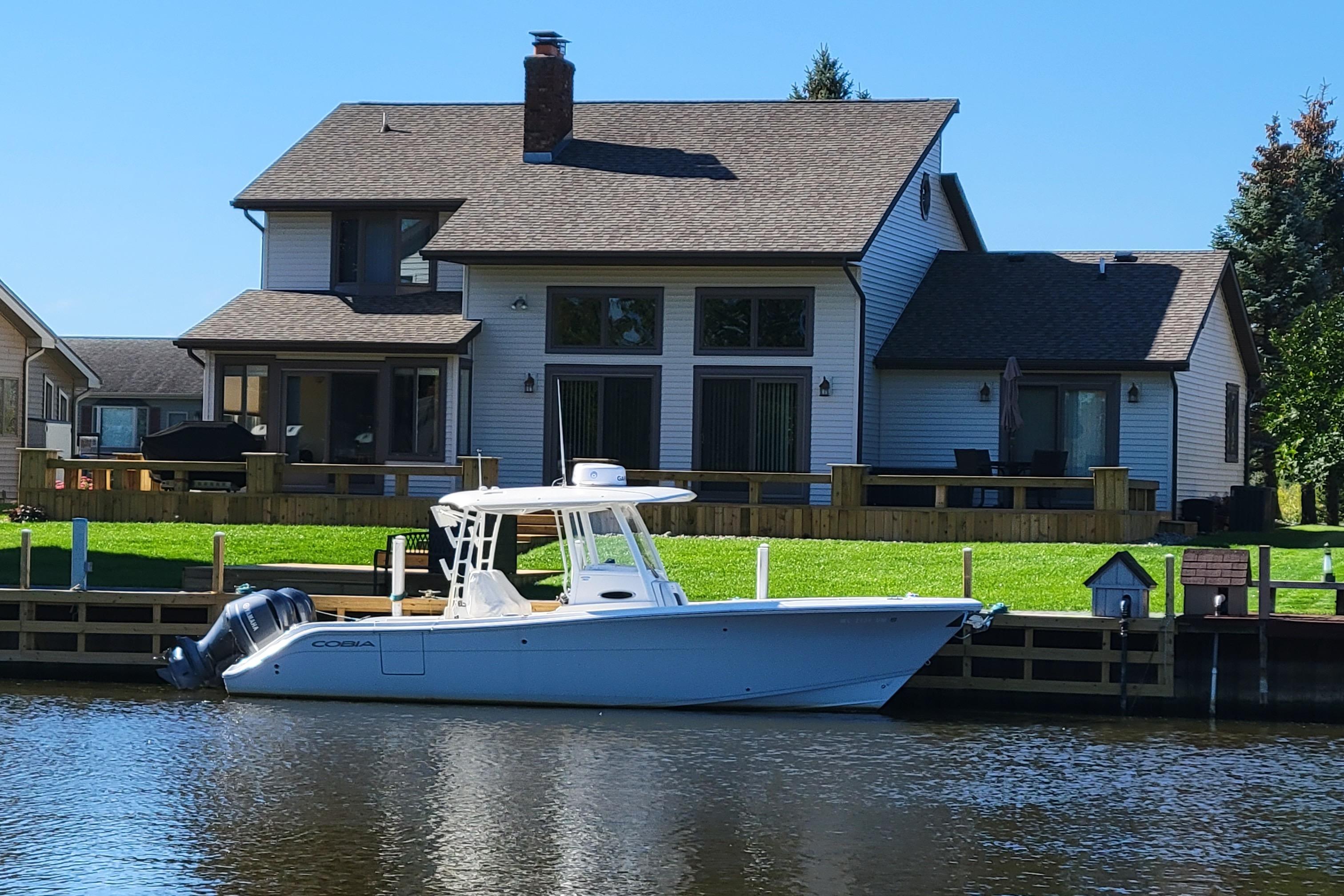 Cobia 301 Center Console 2020 Cobia 301 Center Console boat docked by a lakeside house.