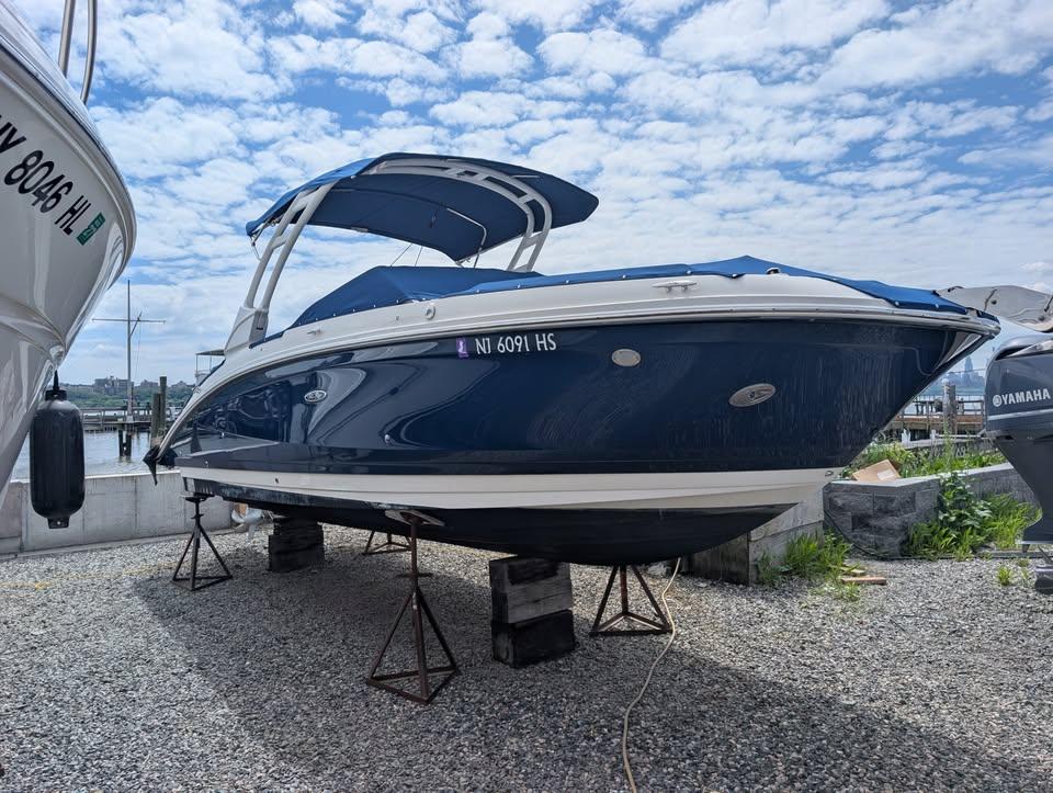 Sea Ray SDX 270 Outboard 2021 Sea Ray SDX 270 Outboard boat on stands, blue hull, marina background.