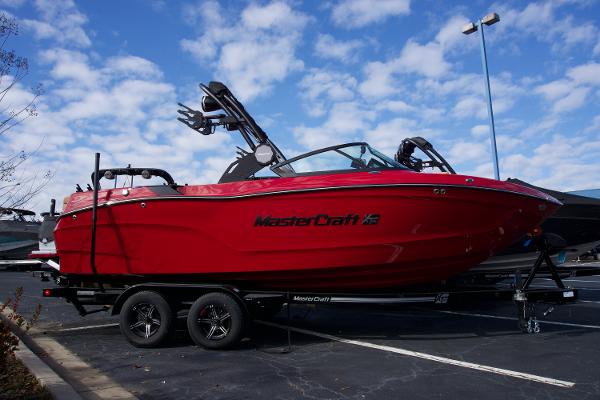 MasterCraft XT22T 2025 MasterCraft XT22T boat in vibrant red on a trailer under a blue sky.