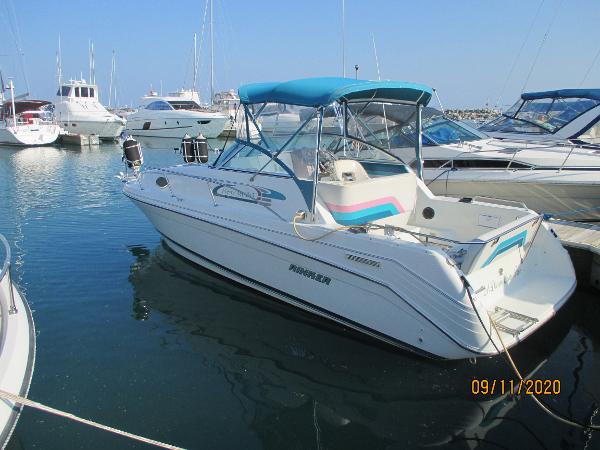 Rinker Fiesta Vee 265 1994 Rinker Fiesta Vee 265 boat docked in marina, featuring blue canopy and white hull.