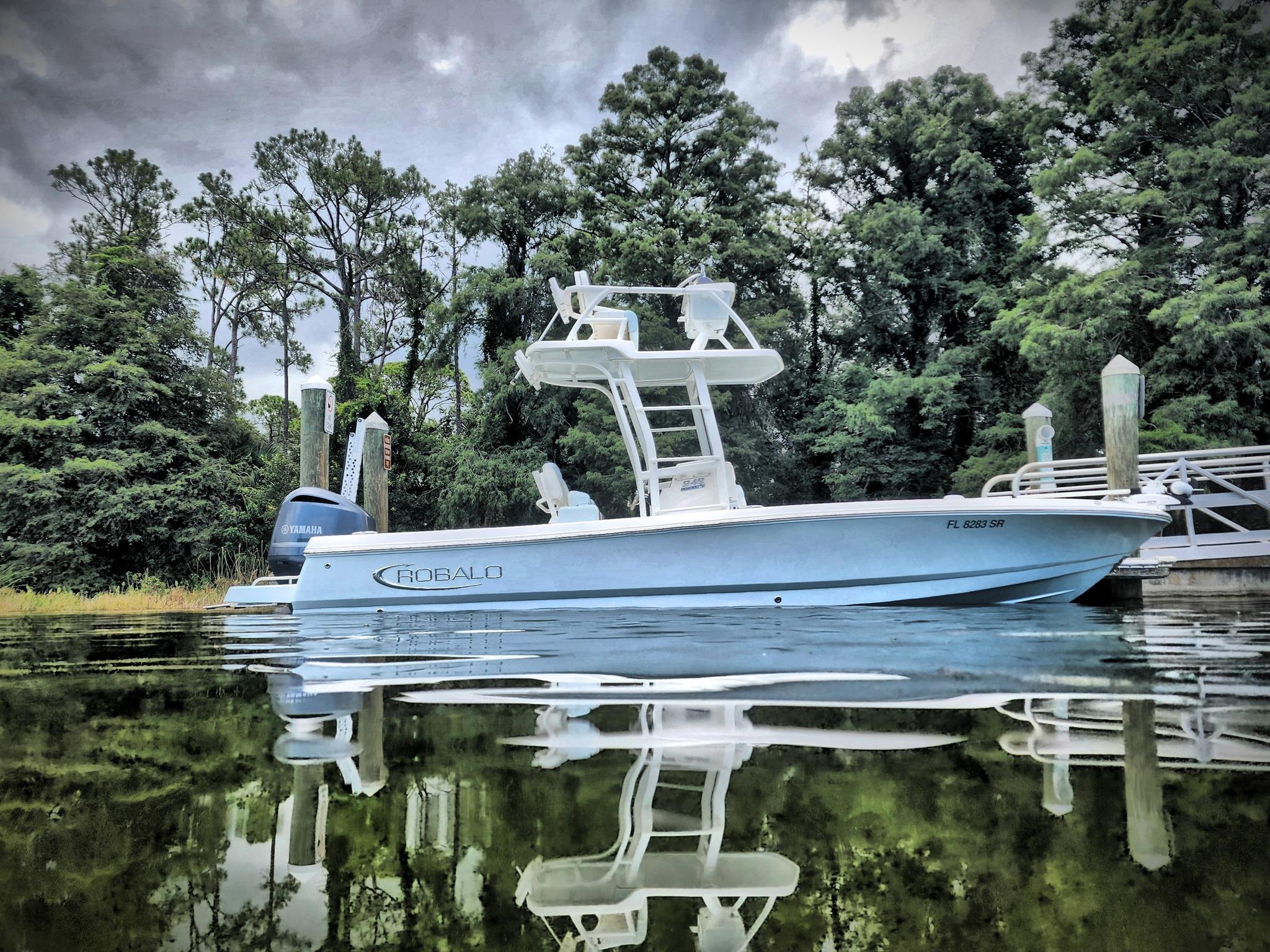 Robalo 246 Cayman 2020 Robalo 246 Cayman boat on calm water, surrounded by lush trees.