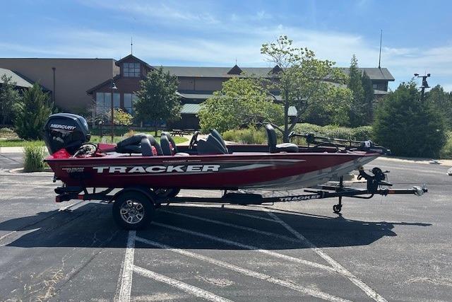 Tracker Pro Team 175 2025 Tracker Pro Team 175 boat on trailer in parking lot, sunny day.