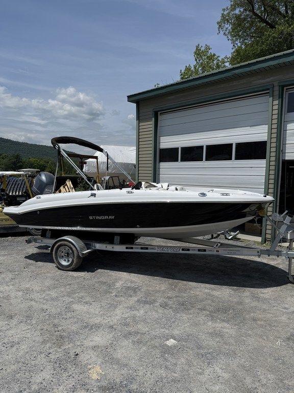 Stingray 182SC 2025 Stingray 182SC boat on trailer, parked outside a garage under a clear sky.