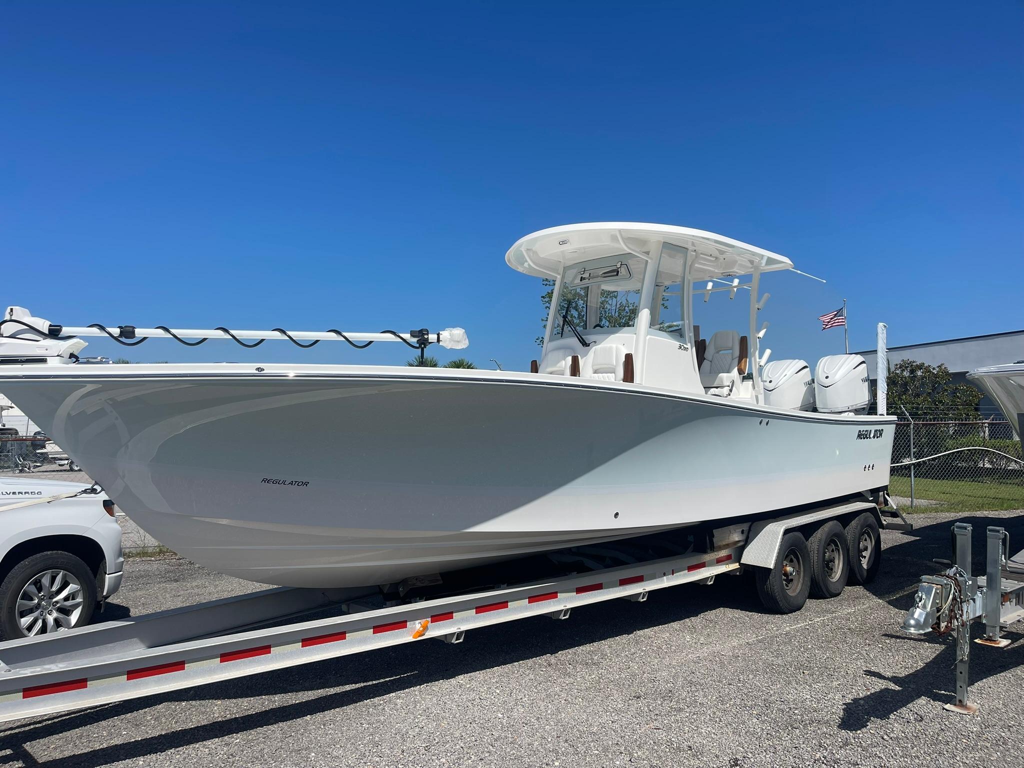 Regulator 30XO 2026 Regulator 30XO boat on trailer, clear sky background, American flag visible.