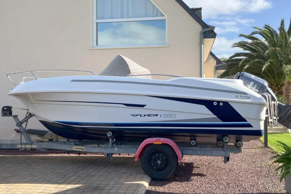 Beneteau Flyer 550 Open 2014 Beneteau Flyer 550 Open boat on trailer, parked near a house with palm trees.
