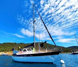 Wauquiez Amphora 1978 Wauquiez Amphora sailboat anchored in scenic bay under blue sky.