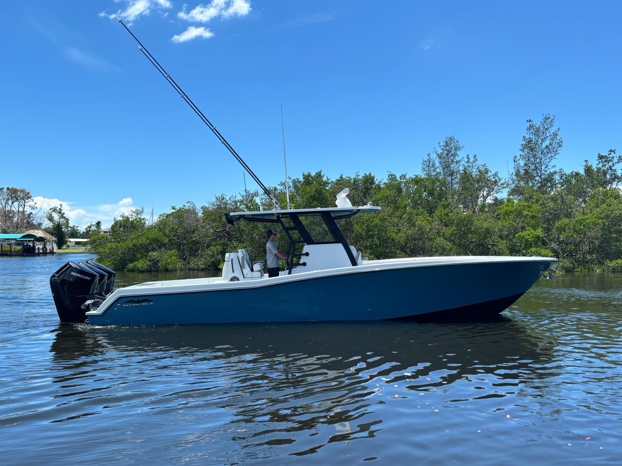 Invincible 36 Open Fisherman 2026 Invincible 36 Open Fisherman boat on calm water, surrounded by lush greenery.