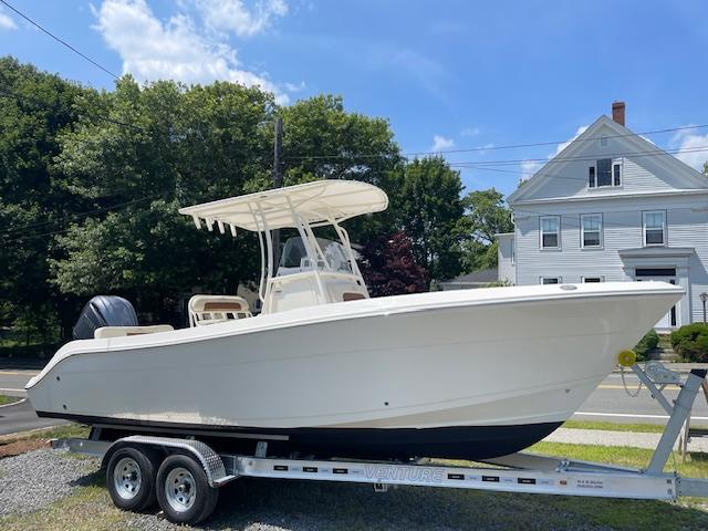 Cobia 237CC 2023 Cobia 237CC boat on trailer, parked outdoors under a clear blue sky.