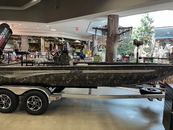 Ranger RB210 2024 Ranger RB210 boat on display in showroom, featuring camouflage design and dual-axle trailer.
