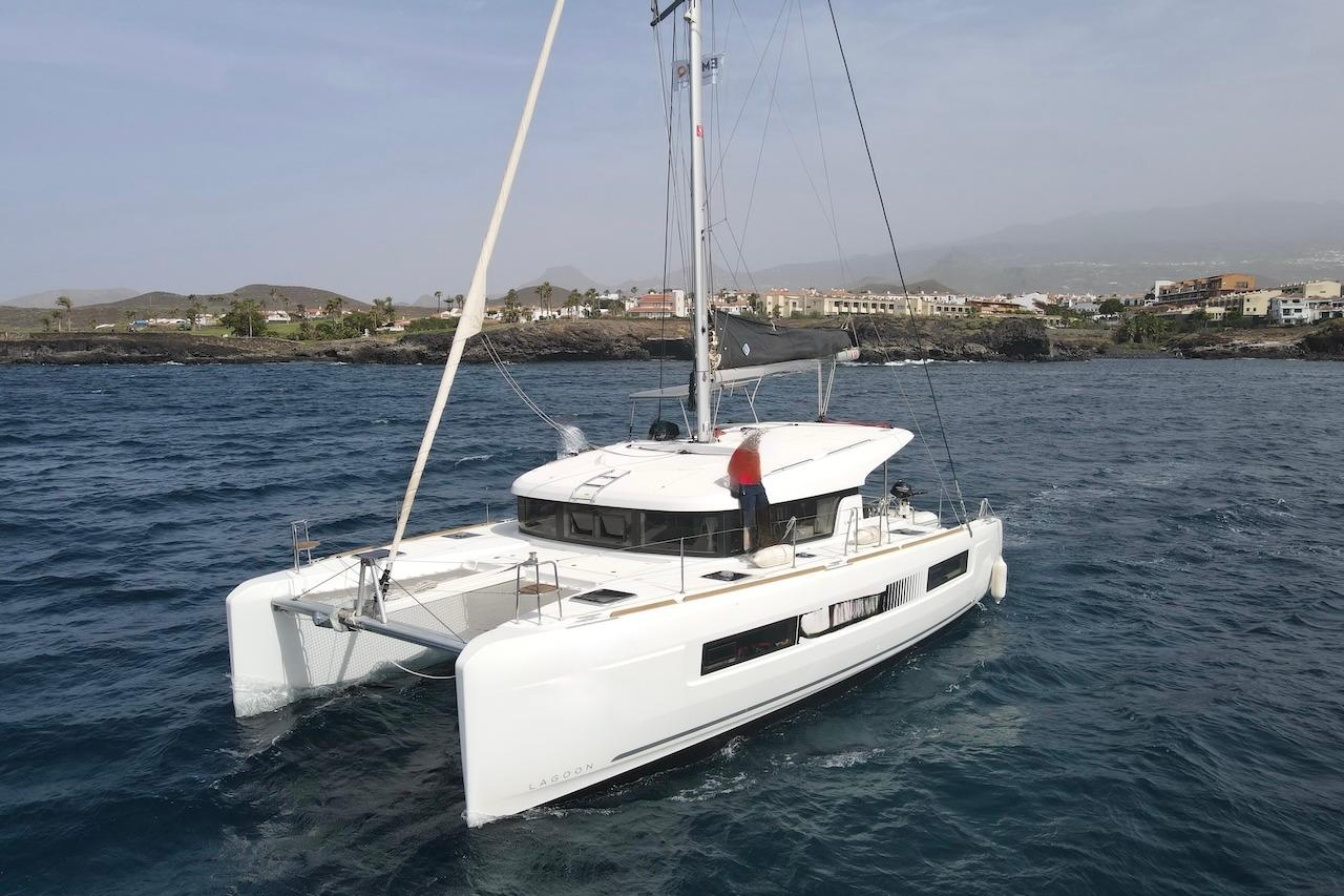 Lagoon 40 2020 Lagoon 40 catamaran sailing near a coastal town, showcasing sleek design and modern features.