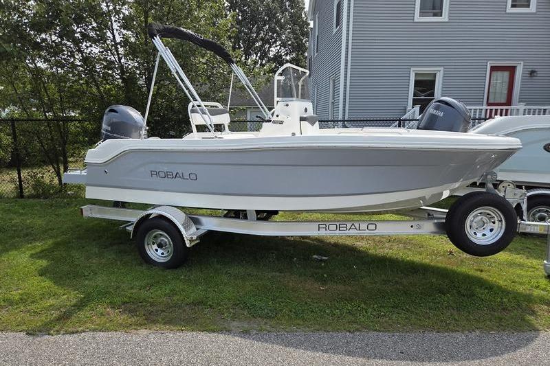 Robalo R160 Center Console 2025 Robalo R160 boat on trailer, parked on grass near a house.
