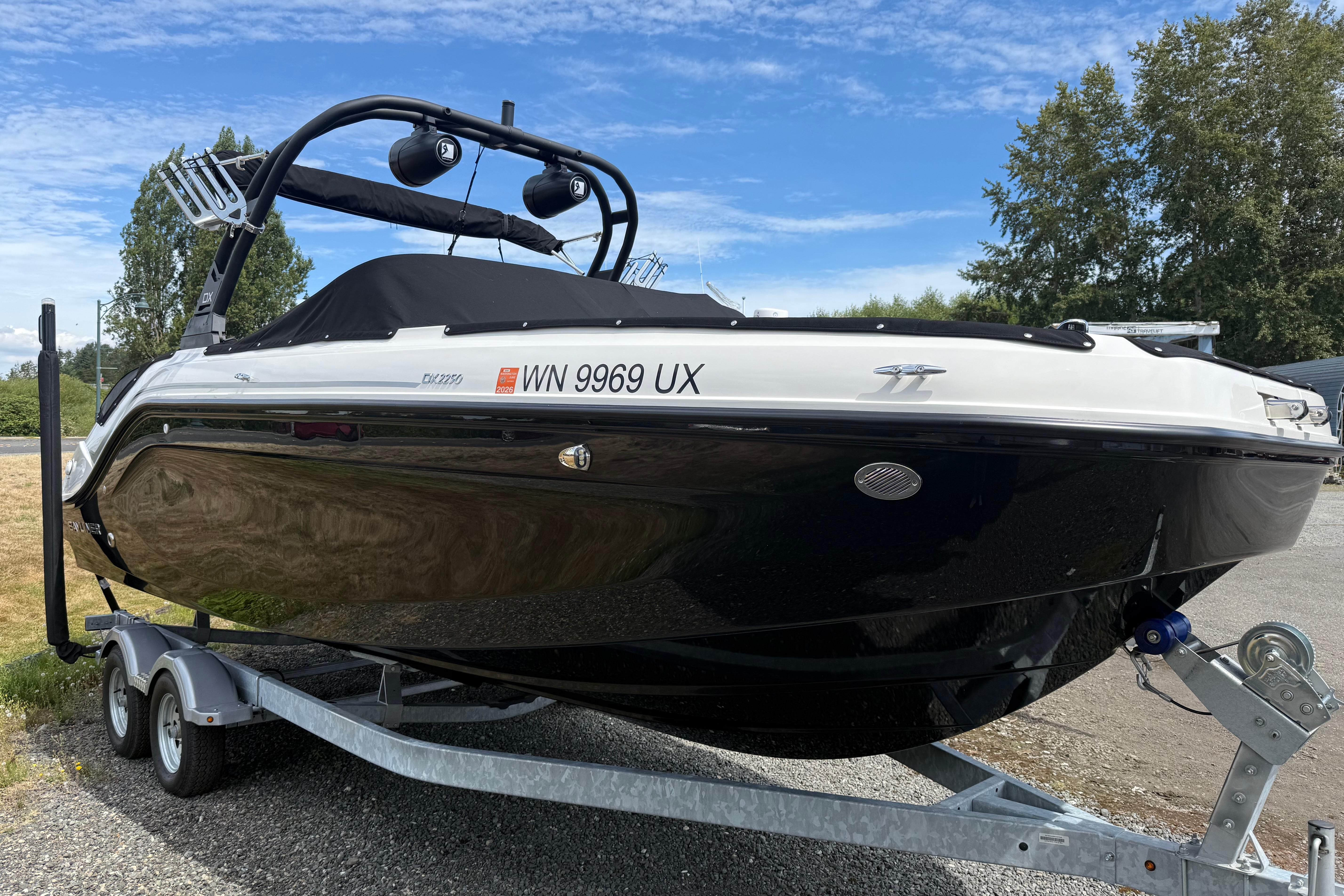 Bayliner DX 2250 2024 Bayliner DX 2250 boat on trailer, parked outdoors under a clear blue sky.