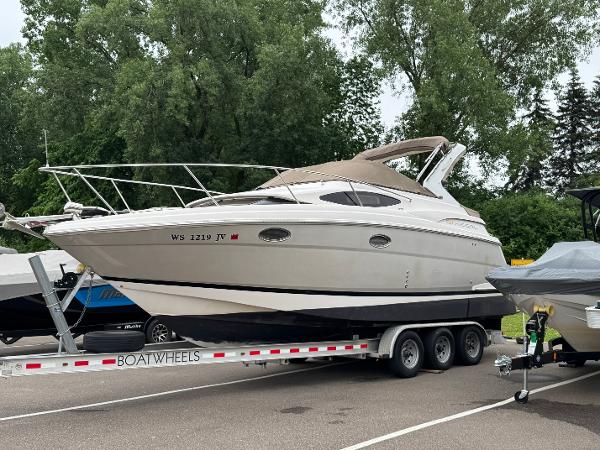 Regal 2860 Window Express 2006 Regal 2860 Window Express boat on trailer, parked outdoors with trees in background.