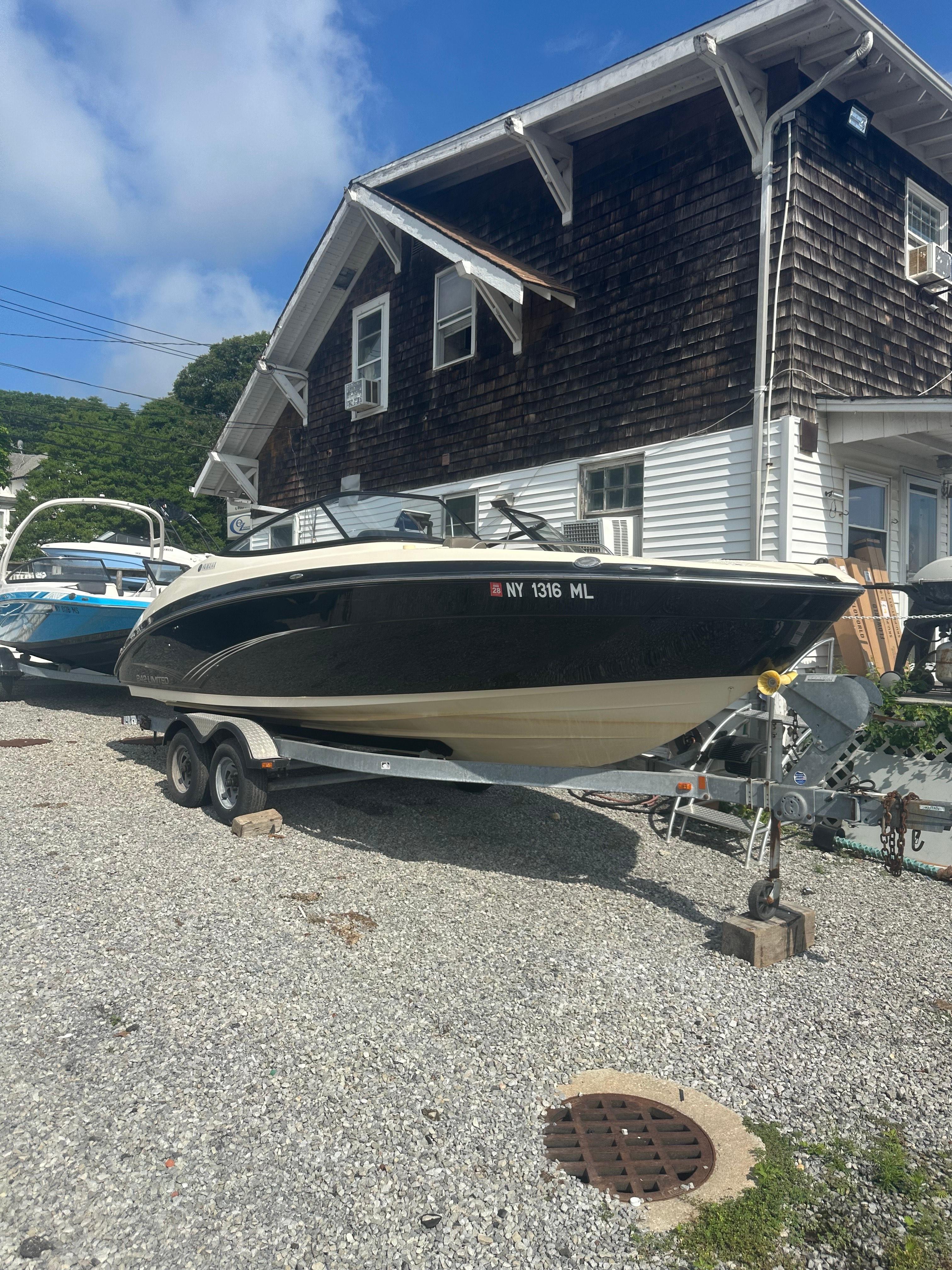 Yamaha Boats 242 Limited 2015 Yamaha Boats 242 Limited on trailer, parked beside a rustic house.