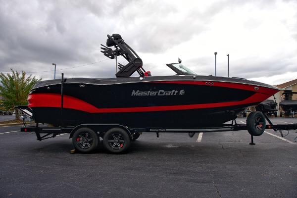 MasterCraft X24 2024 MasterCraft X24 boat on trailer, black and red design, parked outdoors.