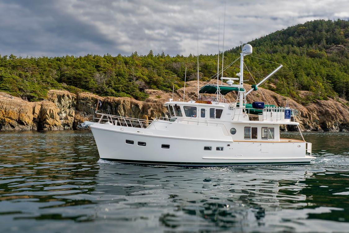 Selene 43 Ocean Classic White Selene 43 yacht cruising near rocky coastline, 2009 model, under cloudy sky.
