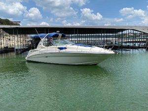Sea Ray 320 Sundancer 2003 Sea Ray 320 Sundancer boat docked on calm water under a blue sky.